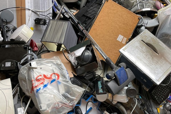 A messy collection of discarded electronic waste - keyboard parts, microwave doors, cords, etc.