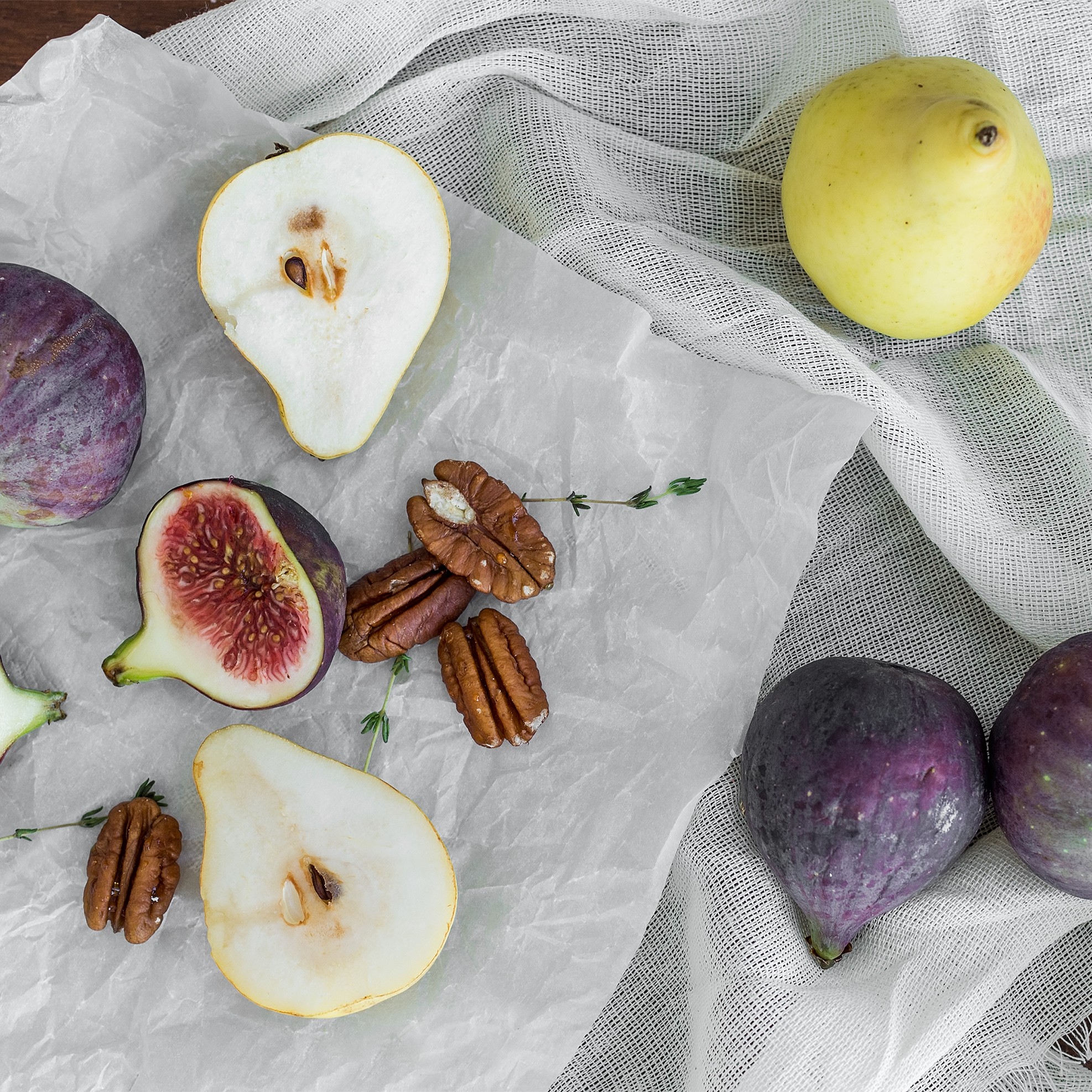 Figs and pears that have been cut open are laying on a cutting board