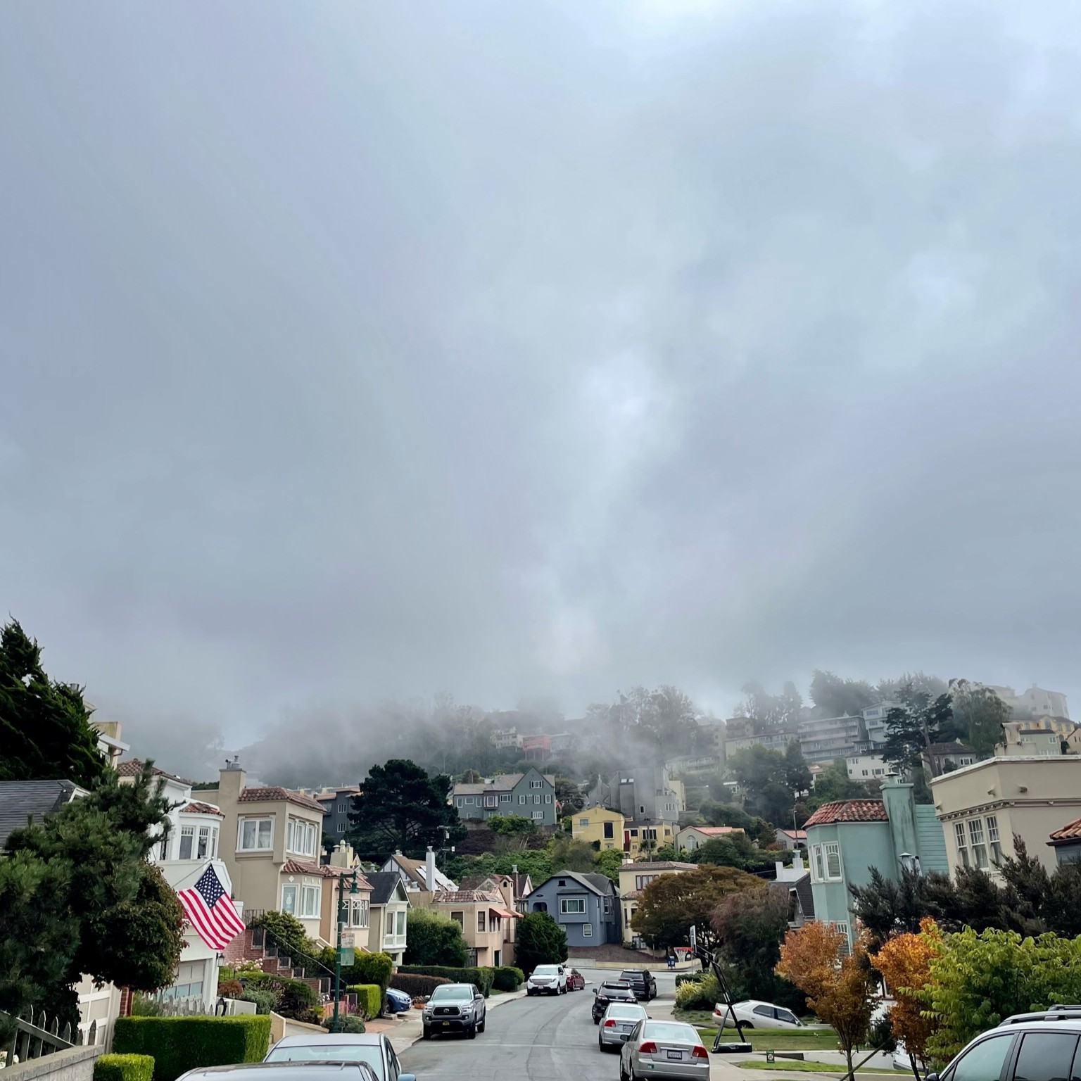 A San Francisco street with fog coming down from the mountain.
